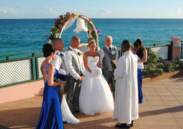 Bride and groom getting married on balcony overlooking beach in Barbados