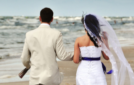 Couple walking along beach after wedding